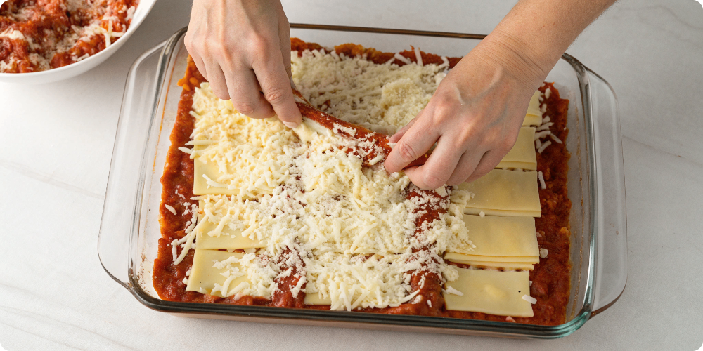 Assembling Ronzoni lasagna recipes in baking dish
